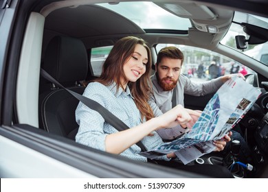 Couple In Car With Map. Man At The Wheel. Side View