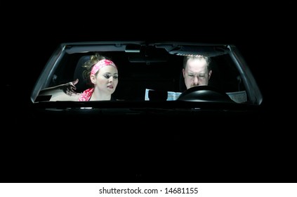 A Couple In A Car At Night Looking At A Map