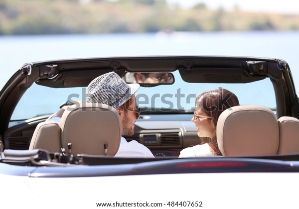 Couple in car on river\
shore
