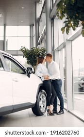 Couple in a car salon. Family buying the car. Elegant woman in a white blouse
