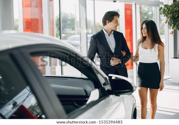Couple in a car salon. Family buying the car.\
Elegant woman with her\
boyfriend
