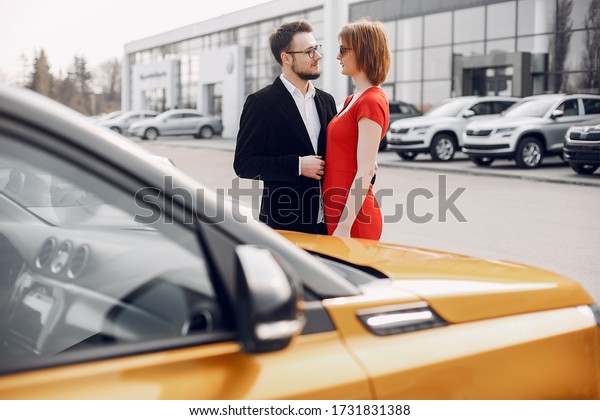 Couple in a car salon. Family buying the car.\
Elegant woman with her\
husband.