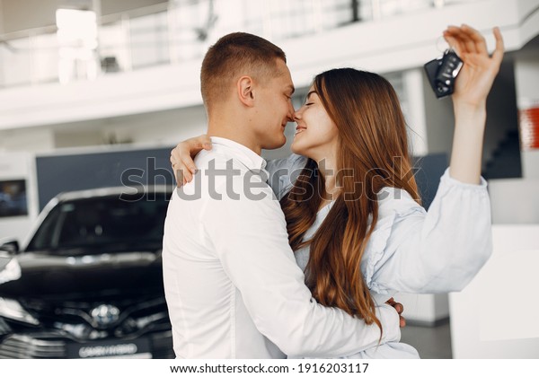 Couple in a car salon. Family buying the car.\
Elegant woman in a white\
blouse
