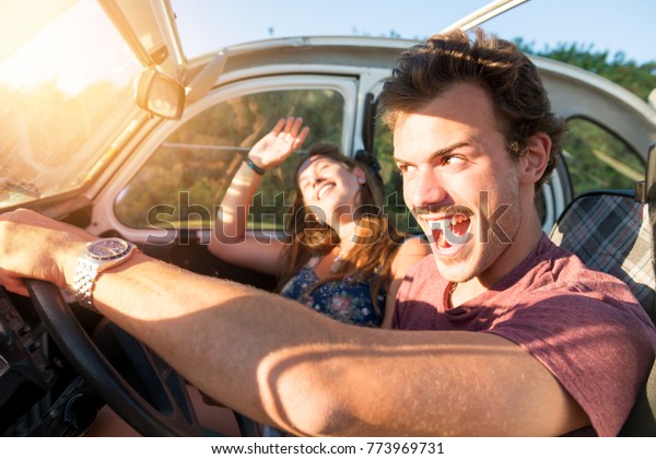 Couple in a car at sunset, with\
male driving fast and girl scared, screaming and\
praying.