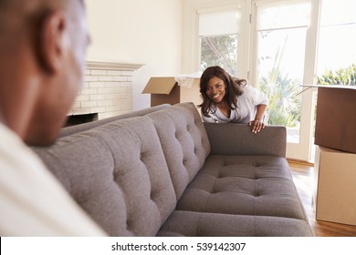 Couple Carrying Sofa Into New Home On Moving Day