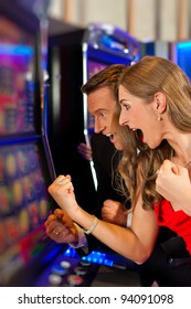 Couple in Casino on a slot machine winning and having fun - Shutterstock ID 94091098