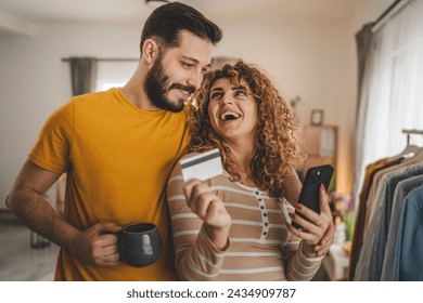 Couple caucasian man and woman husband and wife or boyfriend and girlfriend use mobile phone and credit card shopping online buy stuff or pay make payment booking e-commerce from home real people - Powered by Shutterstock