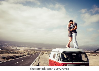 couple of caucasian man and woman people in love standing over the roof of a classic van vintage kissing and hugging. long way road on the side for travel and destination concept - Powered by Shutterstock