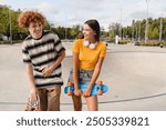 Couple of caucasian teenagers classmates students high school pupils friends boy girl in casual clothes holding skateboard have fun date spend time weekend summer holidays in skate park after lessons