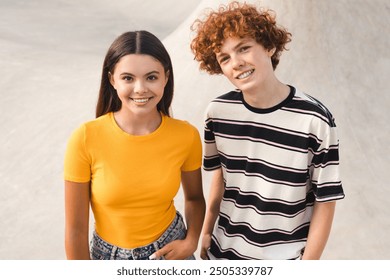 Couple of caucasian teenagers classmates students high school pupils friends boy girl in casual clothes standing posing spend time weekend summer holidays in skate park after lessons looking at camera - Powered by Shutterstock