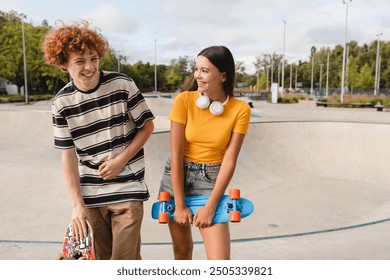 Couple of caucasian teenagers classmates students high school pupils friends boy girl in casual clothes holding skateboard have fun date spend time weekend summer holidays in skate park after lessons - Powered by Shutterstock