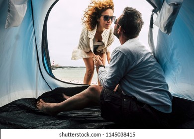 Couple Of Caucasian Woman And Men 40 Years Old In Love Camping At The Beach In Tropical Place, Living Near The Ocean And Enjoying Vacation In Tent. Kiss And Lighthouse In Background