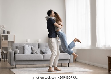 Couple celebrate relocation to new modern apartment, loving husband lifts his overjoyed wife, hugging, feel happy, start living together, enjoy move-in day to newly bought flat. Cohabitation, marriage - Powered by Shutterstock