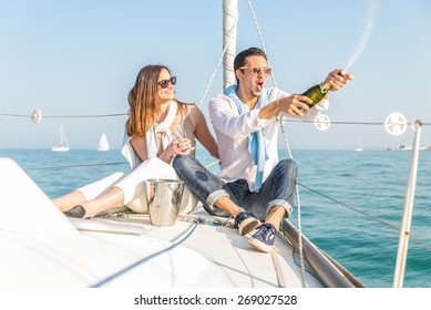 Couple celebrating with champagne on a boat .Attractive man uncorking champagne and having party with girlfriend on vacation.Two young tourists having fun on boat tour in the summertime - Powered by Shutterstock