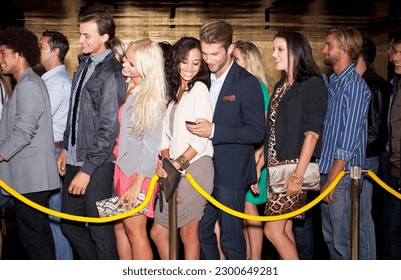 Couple with cell phone standing in queue outside nightclub