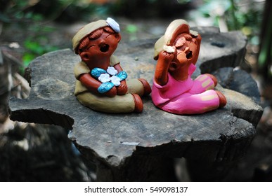 Couple of ceramic model or statue of boy and girl sitting together with smiling face for home or garden decoration