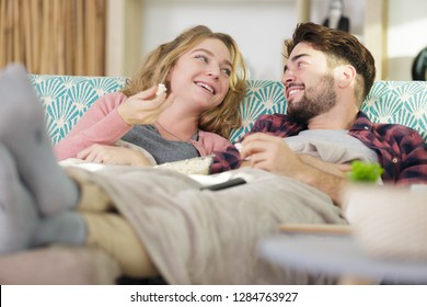 Couple Chatting On The Sofa Snuggled Under A Blanket