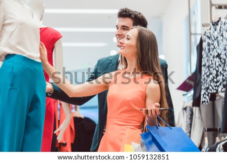 Couple checking the new arrivals in fashion boutique looking at dress colors