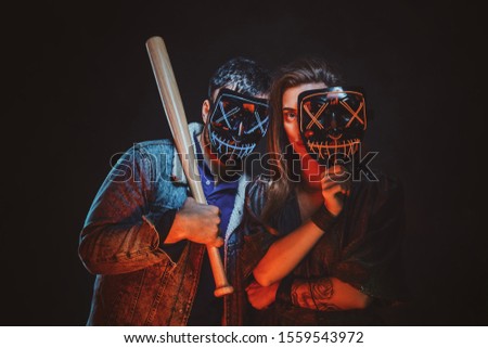 Couple of cheeky lawbreakers are posing for photographer with masks and baseball bat.