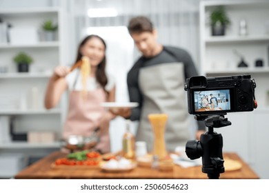 Couple chef influencers cooking special homemade of spaghetti with tongs taking to frying pan, putting seasoning and tasty sauce to make good flavor, recording on camera with live chanel. Postulate. - Powered by Shutterstock