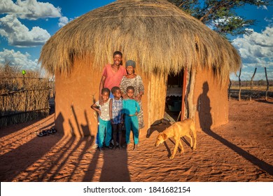 Couple And Children, African Family In Front Of The House With A Thatched Roof, Village In Botswana