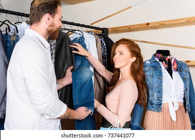 Couple Choosing Clothes On Shopping In Boutique