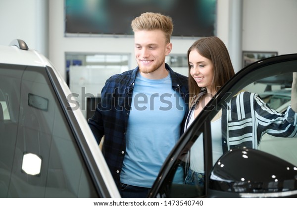 Couple choosing new car in\
salon