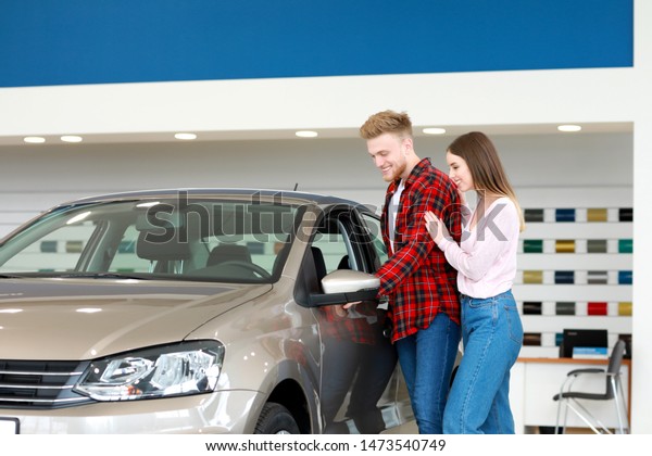 Couple choosing new car in\
salon