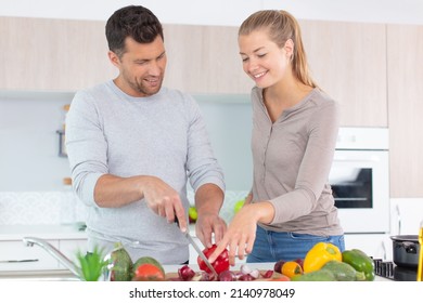 Couple Chopping Vegetables In Preparation For A Meal