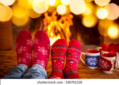 Couple In Christmas Socks Near Fireplace. Man And Woman Having Fun Together. People Relaxing At Home. Winter Holiday Xmas And New Year Concept