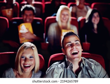 Couple At Cinema Movie Theatre For Funny, Comic And Happy Film Show In Audience Auditorium On A Date. Smile, Relax And Laughing People Watching Comedy Movies On Big Screen In A Dark Theater Together