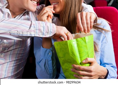 Couple in cinema theater watching a movie, they eating popcorn, close-up
