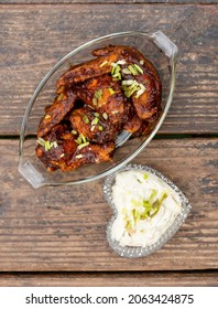 A Couple Of Classic Buffalo Wings In A Glass Platter Served With Ranch Dip In A Heart Shaped Bowl.