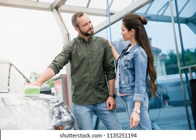 Couple Cleaning Car With Rag And Foam At Car Wash