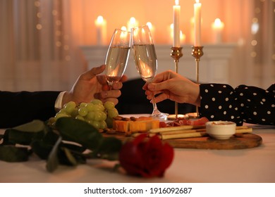 Couple clinking glasses of champagne in restaurant, closeup. Romantic dinner