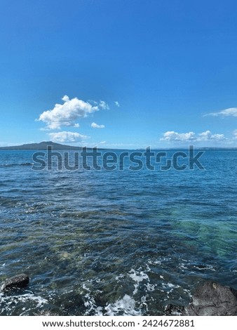 A couple of clouds in the sky above and near rangitoto island.