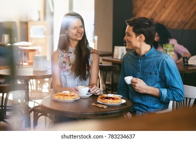 Couple With Coffee On Date. Beautiful Smiling People In Love Drinking Coffee And Talking In Cafe. Happy Young Man And Woman Enjoying Romantic Date With Croissant And Coffee In Bakery. High Quality - Powered by Shutterstock