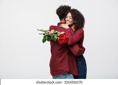 Couple Concept - Young african american couple huging each other and holding romantic red rose.
