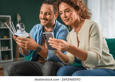 Couple configuring an security cctv camera for home security, connecting it to a mobile phone, and reviewing smart home surveillance technology settings together in a modern interior - Powered by Shutterstock - Get 15% off with code: PIKWIZARD15