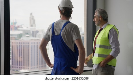 Couple Of Construction Workers On Workplace, Young Electrician Technician And Contractor Foreman Talking Together On Building Site, Engineer And Architect Meeting For Project Working