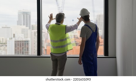 Couple Of Construction Workers On Workplace, Young Electrician Technician And Contractor Foreman Talking Together On Building Site, Engineer And Architect Meeting For Project Working