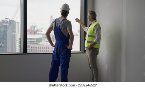 Couple Of Construction Workers On Workplace, Young Electrician Technician And Contractor Foreman Talking Together On Building Site, Engineer And Architect Meeting For Project Working