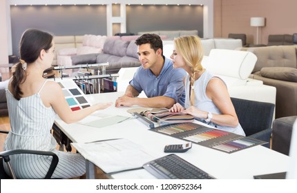 couple consulting with seler about color for new sofa in store