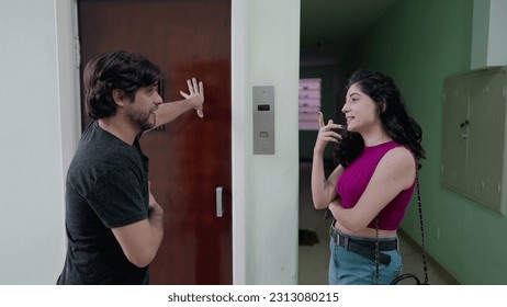 Couple conversing while waiting for elevator at older building. Man and woman going out in conversation while standing at hallway