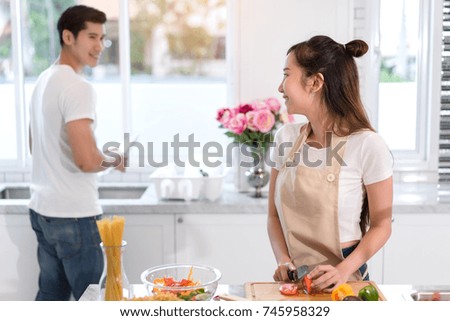Couple cooking food in kitchen room, Young Asian man and woman together cutting slice vegetables making each salad for dinner menu with fruits at home romantic indoor sweet, happy