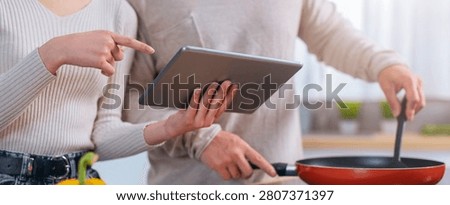 Couple Cooking Together In Kitchen, Using Tablet For Recipe, Engaged And Focused