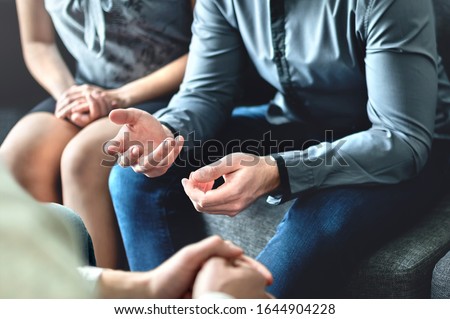 Couple counseling or therapy session. Man talking about problems in the family. Husband and wife meeting their psychiatrist. Discussion with marriage counselor, mediator or relationship psychologist.