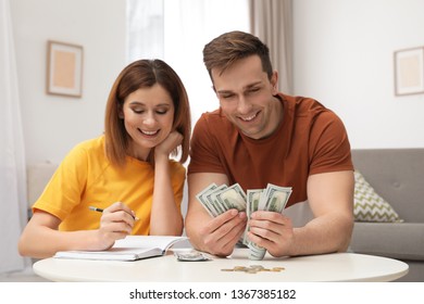 Couple Counting Money At Table In Living Room