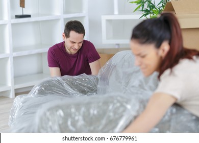 Couple Covering The Sofa With Plastic