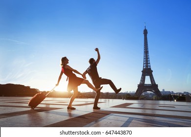 couple of crazy tourists on holidays in Paris, man and woman having fun near Eiffel Tower, travel with luggage, tourism
